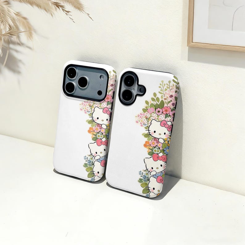 Puede incluir: Dos fundas blancas para tel&eacute;fono con dise&ntilde;o floral y Hello Kitty. Las fundas tienen una disposici&oacute;n vertical de figuras de Hello Kitty con lazos rosas, rodeadas de flores coloridas y hojas verdes.