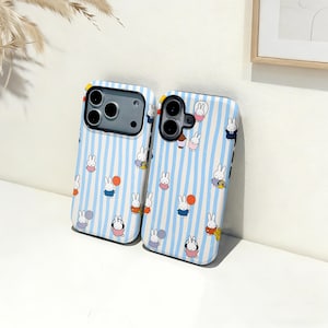 Op de afbeelding: Twee telefoonhoesjes met een blauw-wit gestreept patroon en een herhalend cartoon konijn ontwerp. De konijnen dragen verschillende outfits en houden ballonnen vast. De hoesjes hebben uitsparingen voor de camera en knoppen.