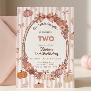 Op de afbeelding: Een rechthoekige verjaardagsuitnodiging met een lichtroze gestreepte achtergrond, voorzien van een ovaal kader versierd met pompoenen, bloemen en strikken. De tekst luidt: Our Little Pumpkin is turning TWO, Olivia's 2nd Birthday, 25 oktober, 14:00 uur.