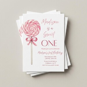 May include: A stack of white invitation cards with a watercolor illustration of a pink lollipop. The text reads "Madison is a Sweet ONE" and invites guests to Madison's first birthday party. Includes date, time, and RSVP information.