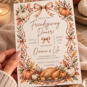 Op de afbeelding: Een rechthoekige uitnodigingskaart voor een Friendsgiving-diner met een rand van oranje en witte pompoenen, herfstbladeren, rode bessen en bruine ruitjesstrikken. De tekst luidt Join us for a Friendsgiving Dinner, Nov 27 6:00 PM, Maple Lane, CA.