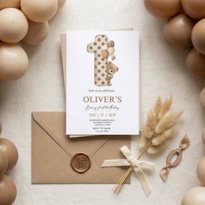 Pode incluir: Um convite de anivers&aacute;rio com tema de ursinho de pel&uacute;cia. O convite apresenta um grande n&uacute;mero um com bolinhas, um ursinho de pel&uacute;cia e o texto "OLIVER'S Beary first birthday". Inclui um envelope marrom com um selo de cera.