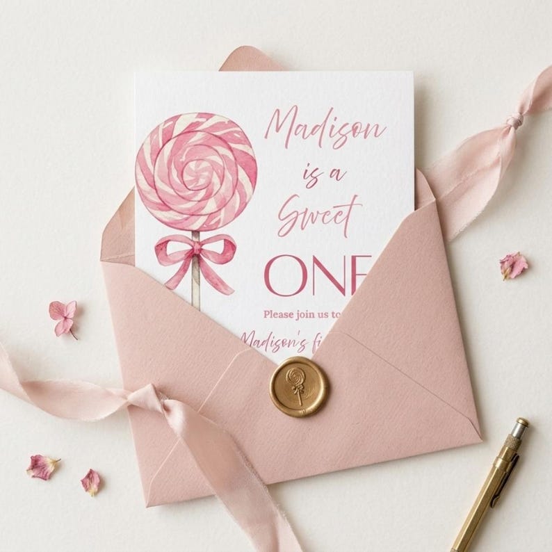 May include: A pink invitation card with a watercolor lollipop illustration, inside a matching envelope. The card reads "Madison is a Sweet ONE" with additional text. A gold wax seal and pink ribbon complete the design, perfect for a first birthday.