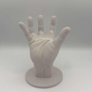 May include: A white ceramic mug with a black handle and the text "But First, Coffee" in a black, handwritten-style font. The mug is on a white surface.