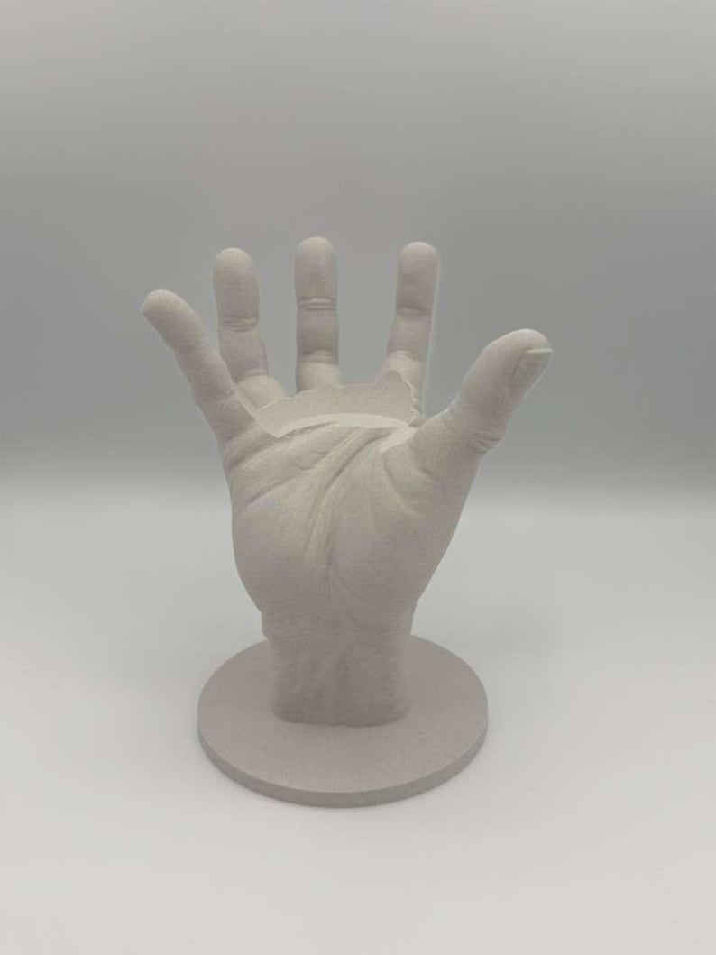 May include: A white ceramic mug with a black handle and the text "But First, Coffee" in a black, handwritten-style font. The mug is on a white surface.