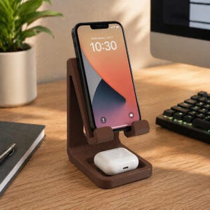 Puede incluir: Un soporte de teléfono de madera marrón que sostiene un teléfono inteligente negro con un fondo de pantalla colorido. El soporte también contiene un par de auriculares inalámbricos blancos. El teléfono muestra "Miércoles, 3 de julio" y la hora "10:30".