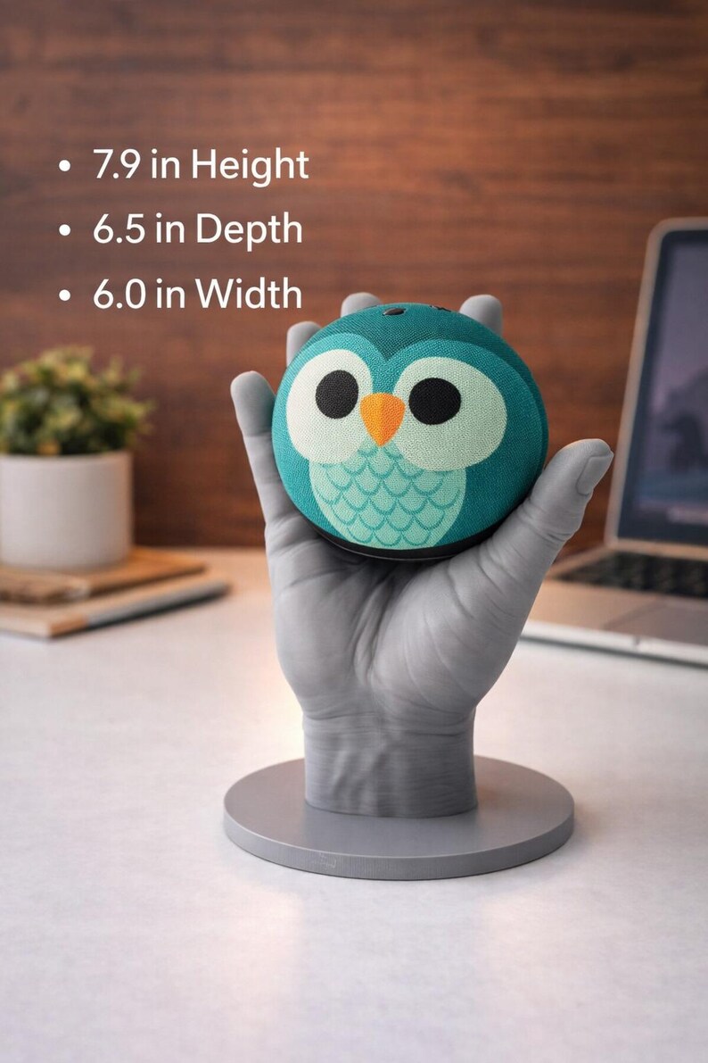 May include: A teal owl-shaped speaker with a white and black face and orange beak, held by a gray hand-shaped stand. The speaker is 7.9 inches high, 6.5 inches deep, and 6.0 inches wide. The speaker has a round shape and a fabric-like texture.