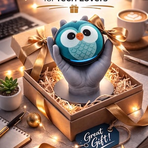 May include: A teal owl-shaped tech gadget is presented in a gift box with a gold ribbon. The box is on a table with a laptop, coffee, and a succulent. The text "Perfect Gift for Tech Lovers" is at the top, and "Great Gift!" is on a tag.