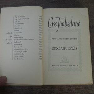 May include: A close-up of a book titled "Cass Timberlane" by Sinclair Lewis. The book cover is white with green text and a decorative border. The back cover lists other novels by Sinclair Lewis with their publication dates.