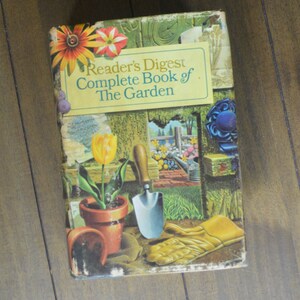 May include: A vintage book titled "Reader's Digest Complete Book of The Garden" with a colorful illustration of a garden scene on the cover. The cover features a yellow tulip, a brown pot, a gardening trowel, and gardening gloves.