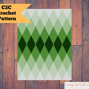 May include: C2C Crochet Pattern with a green diamond pattern on a wood background. The pattern is made up of different shades of green, from light to dark.