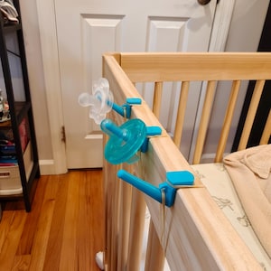 May include: A handmade wooden sign with the word "Welcome" in a playful font. The sign is painted white with a distressed finish, and features a floral design in pinks and greens. It measures approximately 30 cm wide.