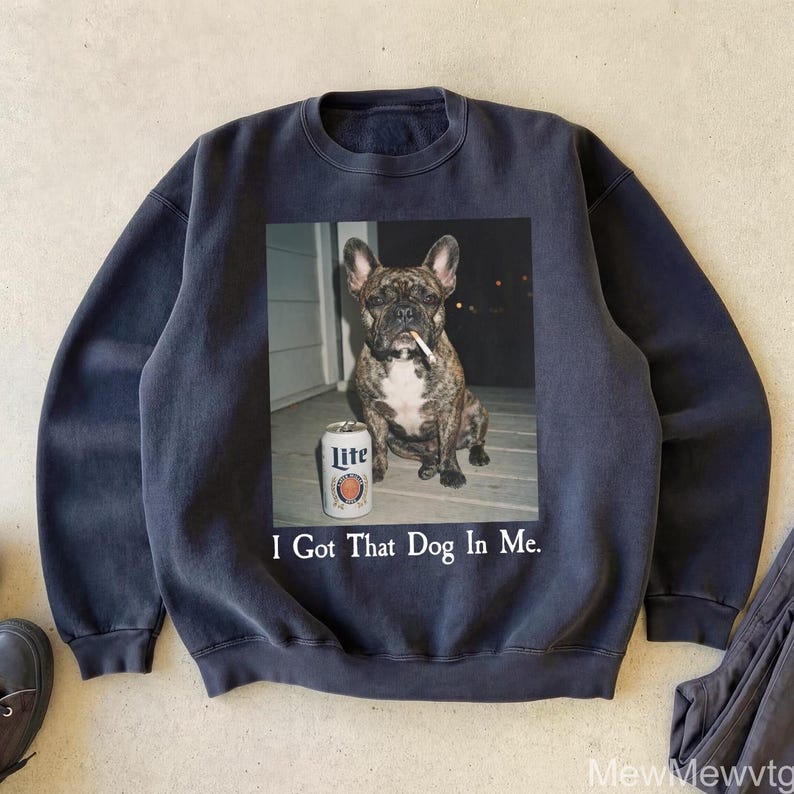 May include: Dark blue sweatshirt featuring a graphic of a brindle French bulldog with a cigarette in its mouth and a can of Lite beer. The text "I Got That Dog In Me" is printed below the image.
