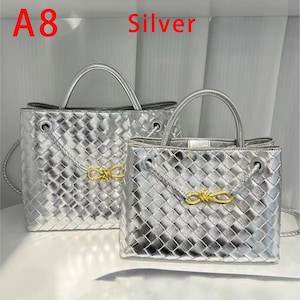 K&ouml;nnte beinhalten: Zwei silberne Handtaschen mit gewebter Textur. Die Taschen haben obere Griffe und goldfarbene Akzente. Das Wort "Silver" ist rot oben im Bild gedruckt. Die Taschen sind unterschiedlich gro&szlig;.