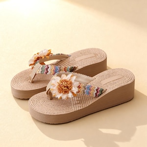 May include: A pair of beige wedge sandals with a woven texture. Each sandal features a colorful zigzag strap and a large, decorative flower. The sandals have a slight platform and a thong-style design, perfect for casual wear.