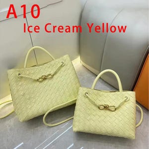 K&ouml;nnte beinhalten: Zwei gewebte, eiscremegelbe Handtaschen mit oberen Griffen und goldfarbenen Akzenten. Die Taschen haben eine rechteckige Form und einen geflochtenen Schulterriemen. Der Text "A10 Ice Cream Yellow" ist sichtbar.