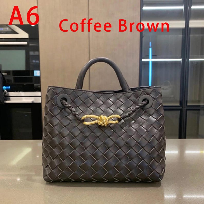 K&ouml;nnte beinhalten: Eine kaffeebraune Handtasche mit gewebtem Design. Die Tasche hat einen oberen Griff und einen goldfarbenen Verschluss. Der Text "A6 Coffee Brown" ist im Bild zu sehen.