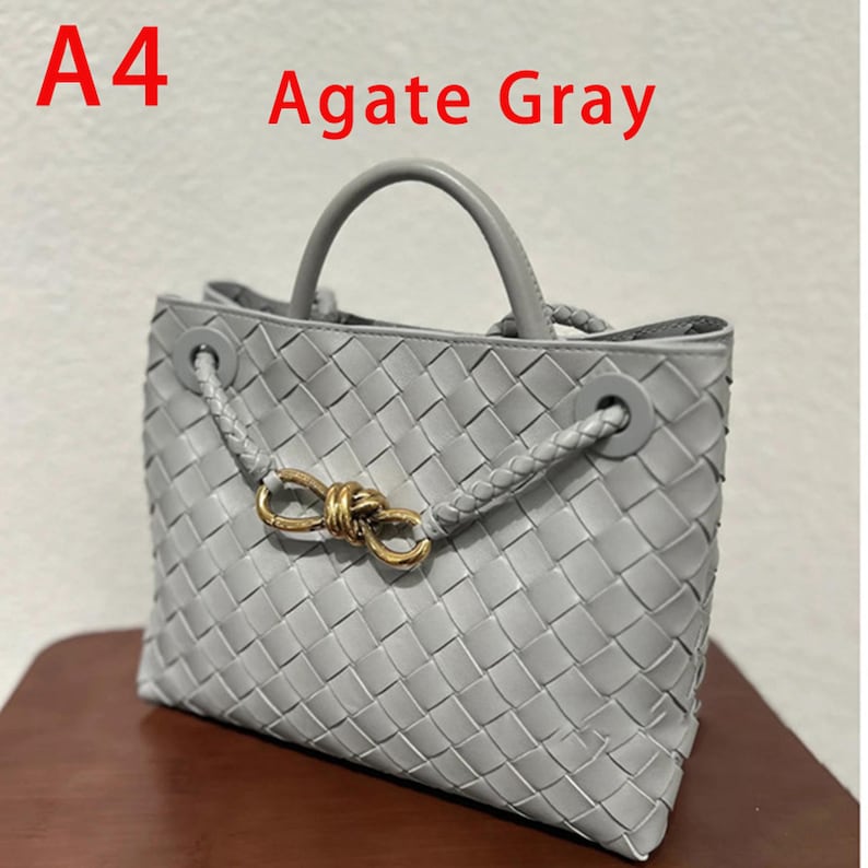K&ouml;nnte beinhalten: Graue Handtasche mit gewebtem Design. Die Tasche hat einen oberen Griff und einen geflochtenen Riemen mit einem goldfarbenen Verschluss. Der Text "A4 Agate Gray" ist oben links sichtbar.