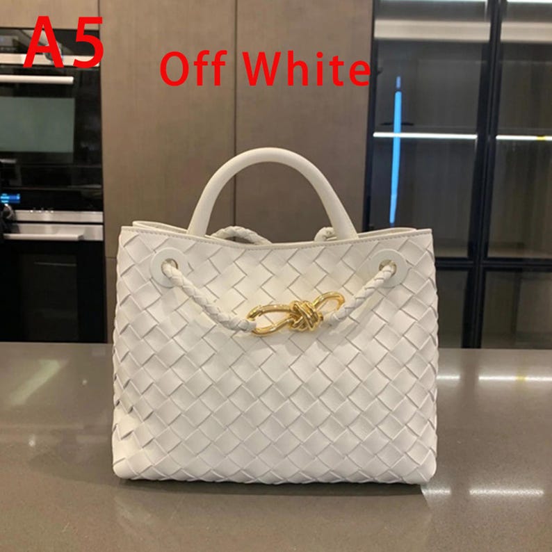 K&ouml;nnte beinhalten: Cremefarbene Handtasche mit gewebtem Design. Die Tasche hat einen oberen Griff, geflochtene Seildetails und einen goldfarbenen Verschluss. Der Text "Off White" ist sichtbar.