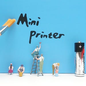 Puede incluir: Una superficie azul claro con el texto negro Mini Printer, que incluye un pincel, cuatro figuras de trabajadores en miniatura y una pila AA Energizer. Las figuras aparecen en varias poses, incluyendo subidas a una escalera y con cubos.