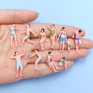 Könnte beinhalten: Eine Sammlung von elf Miniatur-Kunststofffiguren, die Menschen in Badekleidung darstellen, darunter verschiedene Posen wie Stehen, Sitzen und Ballspielen. Die Figuren tragen Badebekleidung in verschiedenen Farben wie Türkis, Gelb, Grün, Blau und Pink.
