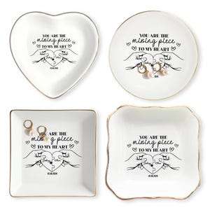 May include: Four white ceramic ring dishes with gold trim. Each dish has the text "YOU ARE THE missing piece TO MY HEART" and a graphic of hands holding a puzzle piece. Some dishes hold earrings.