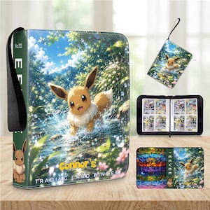 Op de afbeelding: Een rechthoekige verzamelkaartenmap met een bruine Eevee in een bosbeek op de kaft met de tekst Connor's Trading Card Binder. De map bevat een zwarte draagriem, een open binnenkant met kaartsleuven en een bijpassend polsbandje.