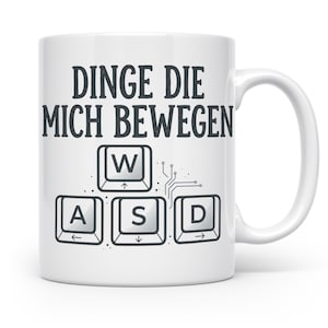 Könnte beinhalten: Eine weiße Keramiktasse mit dem schwarzen Text DINGE DIE MICH BEWEGEN über einer Grafik von vier Computertastaturtasten mit den Buchstaben W, A, S und D. Die Tasten sind in einer Gaming-Anordnung mit kleinen Leiterbahnlinien nach rechts dargestellt.