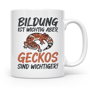 Könnte beinhalten: Ein weißer Keramikbecher mit einer Grafik eines gefleckten Leopardgeckos in der Mitte. Der in Schwarz und Orange gedruckte Text lautet: BILDUNG IST WICHTIG ABER GECKOS SIND WICHTIGER! Der Becher hat eine zylindrische Standardform mit einem Henkel.