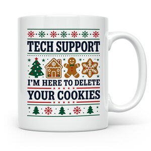 Könnte beinhalten: Ein weißer Keramikbecher mit einem festlichen Weihnachtsmuster aus roten und grünen Schneeflocken, einem Weihnachtsbaum, einem Lebkuchenhaus, einem Lebkuchenmann und einem Schneeflockenkeks. Der Text lautet: TECH SUPPORT I'M HERE TO DELETE YOUR COOKIES.