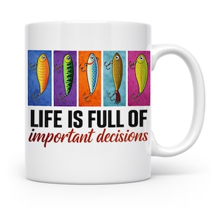 Könnte beinhalten: Ein weißer Keramikbecher mit fünf farbenfrohen Angelköder-Illustrationen in vertikalen rechteckigen Feldern über dem schwarzen und roten Text, LIFE IS FULL OF important decisions, und einem geschwungenen Henkel auf der rechten Seite.
