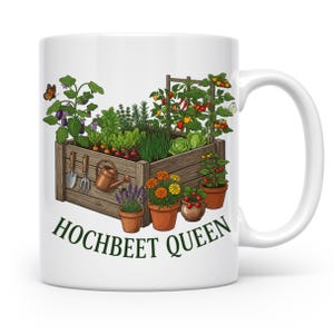 Könnte beinhalten: Weißer Keramikbecher mit einer farbenfrohen Illustration eines Hochbeets voller Gemüse, Kräuter und Blumen. Das Design umfasst Gartengeräte und Topfpflanzen. Der Text "HOCHBEET QUEEN" ist grün gedruckt.