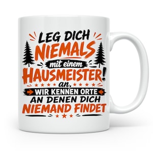 Könnte beinhalten: Eine weiße Keramiktasse mit schwarzem und orangefarbenem Text: LEG DICH NIEMALS mit einem HAUSMEISTER an, WIR KENNEN ORTE AN DENEN DICH NIEMAND FINDET. Das Design enthält zwei schwarze Tannenbäume und kleine Sterne als Akzente.