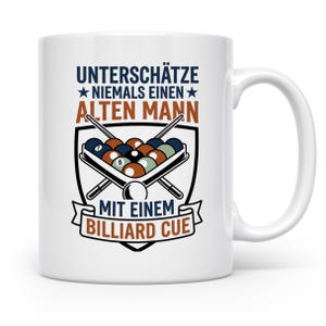Könnte beinhalten: Ein weißer Keramikbecher mit einer Grafik eines Billard-Dreiecks mit farbigen Kugeln und zwei gekreuzten Queues in einem Wappen. Der Text lautet: UNTERSCHÄTZE NIEMALS EINEN ALTEN MANN MIT EINEM BILLIARD CUE in blauer, brauner und schwarzer Farbe.