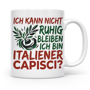 Könnte beinhalten: Eine weiße Keramiktasse mit einer Abbildung eines Olivenzweigs und dem deutschen Text ICH KANN NICHT RUHIG BLEIBEN ICH BIN ITALIENER CAPISCI? Der Text ist in Rot und Dunkelgrün gedruckt, die Olivenzweig-Illustration ist in Dunkelgrün und Schwarz.