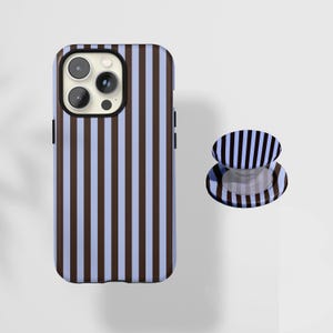 May include: A phone case and matching phone grip with a vertical striped pattern in brown and light blue. The phone case is on the left, and the phone grip is on the right. The phone case has a black camera module.