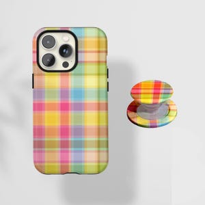 May include: A colorful phone case and matching phone grip. The case and grip feature a plaid pattern in shades of yellow, pink, green, blue, and orange. The phone case has a black border and a camera cutout.