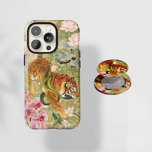 May include: A phone case and phone grip featuring a tiger design. The case has a black border and a colorful illustration of a tiger amidst flowers and foliage. The phone grip has a matching design.