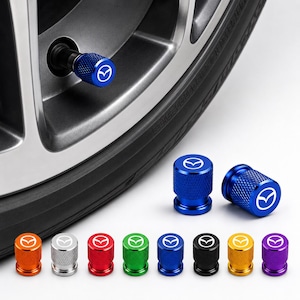 Puede incluir: Un conjunto de tapas cilíndricas para válvulas de neumáticos con un agarre moleteado texturizado y el logotipo de Mazda impreso en blanco en la parte superior. Las tapas están disponibles en varios colores metálicos, incluyendo azul, naranja, plata, rojo, verde, negro, oro y morado.