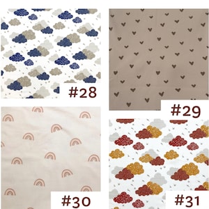 May include: Four fabric swatches labeled #28 through #31. #28 features navy and beige clouds on white. #29 shows brown hearts on a ribbed beige background. #30 displays small pink rainbows on a light background. #31 shows red and gold clouds on white.