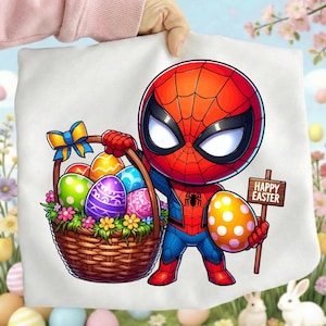 May include: A white graphic tee featuring a cartoon Spider-Man character holding a basket of Easter eggs and a sign that says "Happy Easter". The basket is filled with colorful eggs and flowers. The character is wearing a red and blue suit.