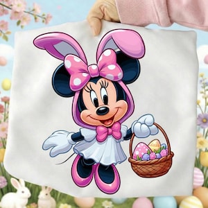 May include: A white tote bag featuring Minnie Mouse dressed as an Easter bunny. Minnie Mouse is wearing a pink bow with white polka dots, a pink bunny ear hood, and holding a basket of Easter eggs.