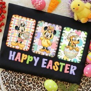 Puede incluir: Camiseta negra con un gráfico colorido de "Felices Pascuas". Presenta a Mickey Mouse como el Conejo de Pascua, Minnie Mouse con un disfraz de pollito y Pluto saliendo de un huevo. Diseño temático de Pascua.
