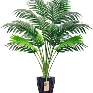 May include: Artificial palm tree in a black geometric pot. The plant features multiple green fronds of varying shades, creating a full and lush appearance. The pot has a textured surface and a tag hanging from it. A decorative item for home or office.