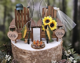 May include: A wedding cake topper featuring two wooden chairs with fishing poles, a campfire, and two fish. The chairs are decorated with the words "Mr." and "Mrs." and a sunflower.