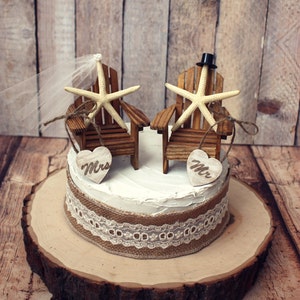 May include: A rustic wedding cake topper featuring two miniature wooden chairs with starfish accents. The chairs are decorated with burlap and lace, and the words "Mr." and "Mrs." are displayed on wooden hearts.