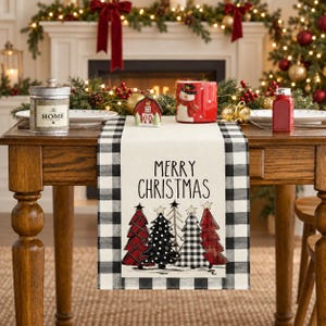 Peut inclure: Un chemin de table rectangulaire avec une bordure à carreaux noirs et blancs et un panneau central crème. Le centre affiche le texte MERRY CHRISTMAS en lettres noires au-dessus d'une rangée de cinq sapins de Noël stylisés rouges, noirs et blancs.
