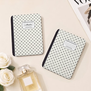 May include: Two composition books with a white cover featuring a black polka dot pattern and a black spine. Each book has a white label with the text COMPOSITION BOOK, 100 sheets 200 pages, and 9.75 x 7.5 in / 24.7 x 19.0 cm. One label includes the name Amelia.