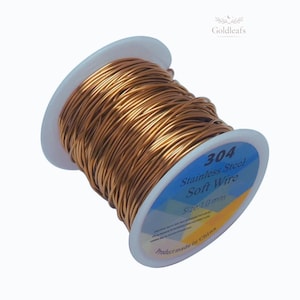 Pode incluir: Um carretel de fio macio de aço inoxidável 304 de cor cobre. O rótulo indica um tamanho de fio de 1,0 mm. O fio é enrolado firmemente em um carretel de plástico branco. O produto é rotulado como fabricado na China.