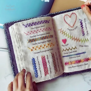 May include: An embroidery sampler book with off-white fabric pages featuring various colourful stitched patterns. Labeled stitches include Herringbone, Deerfield Herringbone, Double Herringbone, Crossed Herringbone, Coral Knot, Zigzag Coral, Satin, Cretan, Cretan Catch, Palestrina, and Long Armed Palestrina.